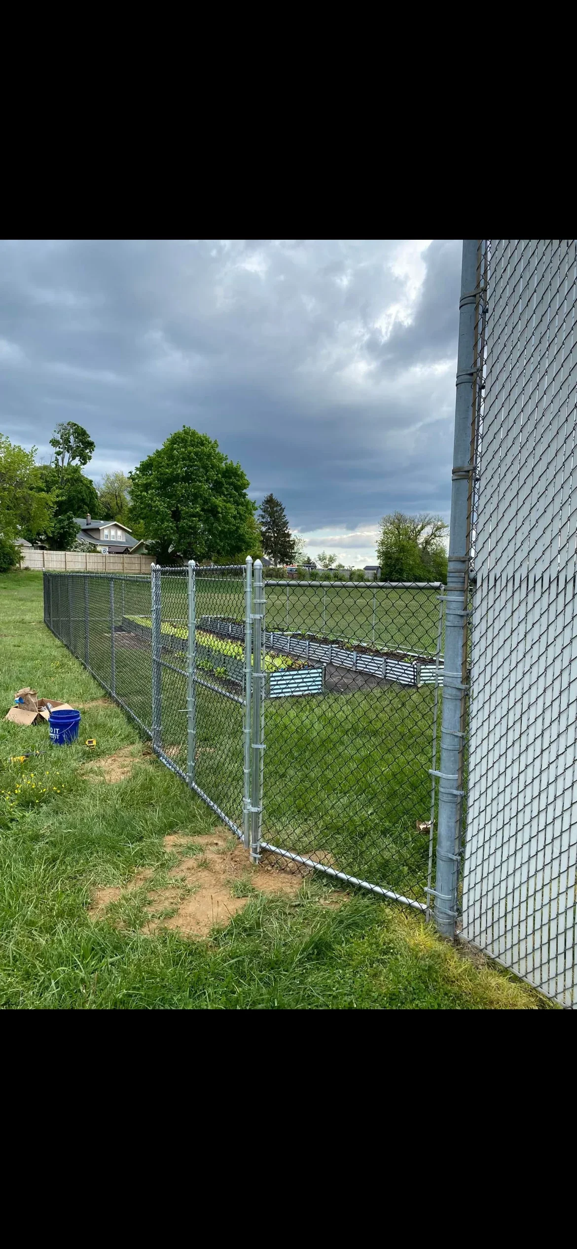 Galvanized chain link fence with white posts and rails installed along residential property
