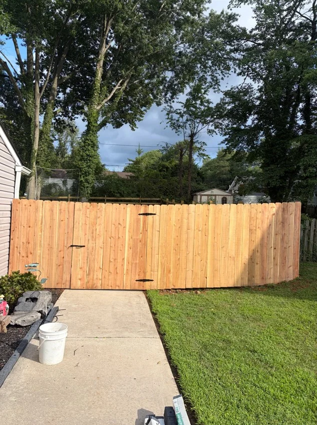 Cedar privacy fence with double gates and black hardware in residential backyard