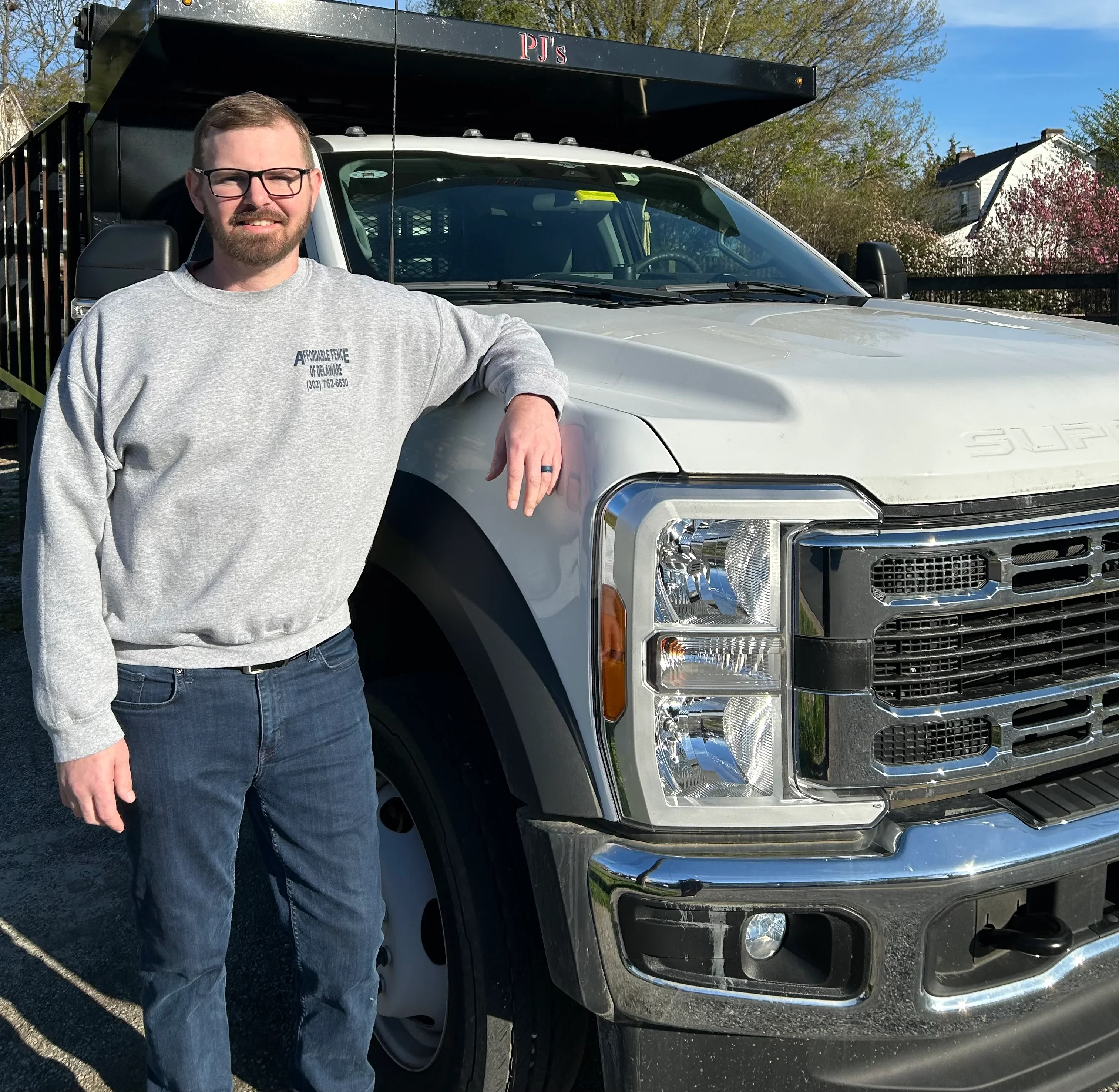 Silver pickup truck with black steel flatbed trailer for fence material transport