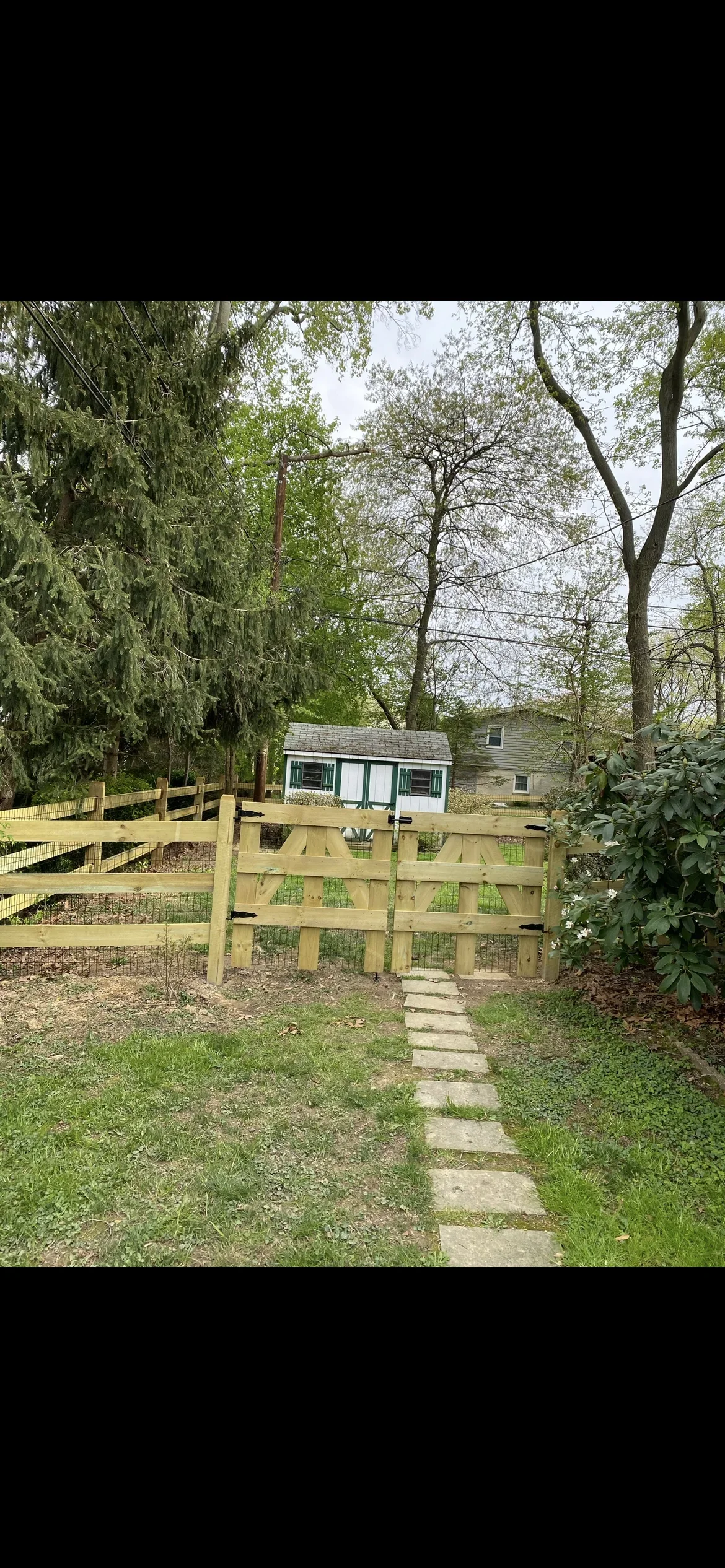 Horizontal wood fence with gate and stone pathway through residential yard